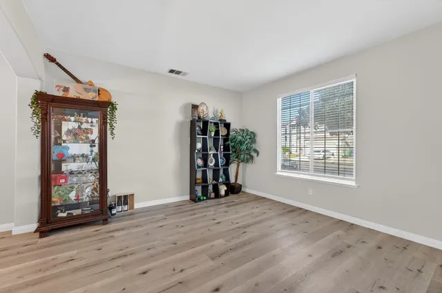 a view of an empty room with window and hardwood floor