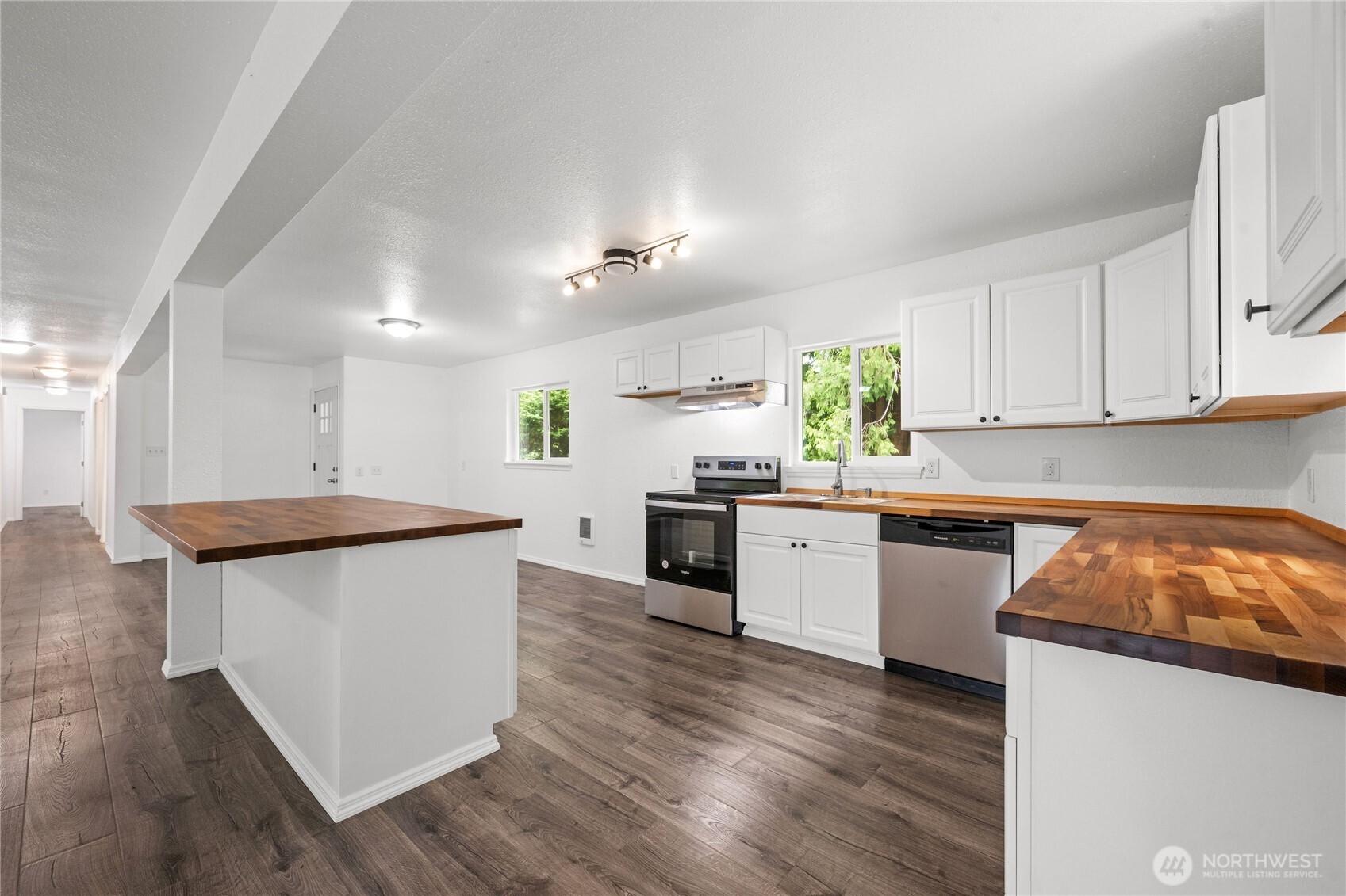 2693 Highway 101 Long Beach, WA 98631 - Photo 11 of 31 a kitchen with granite countertop a stove top oven a sink dishwasher and white cabinets with wooden floor