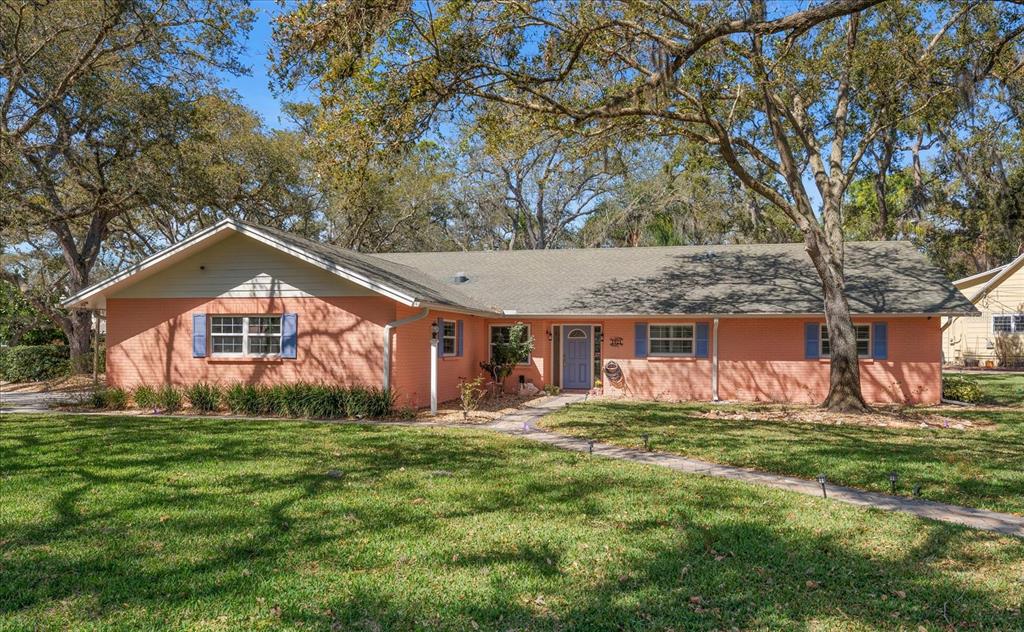 1921 Cardinal Road Dunedin, FL 34698 - Photo 1 of 52 a front view of house with yard and trees in the background