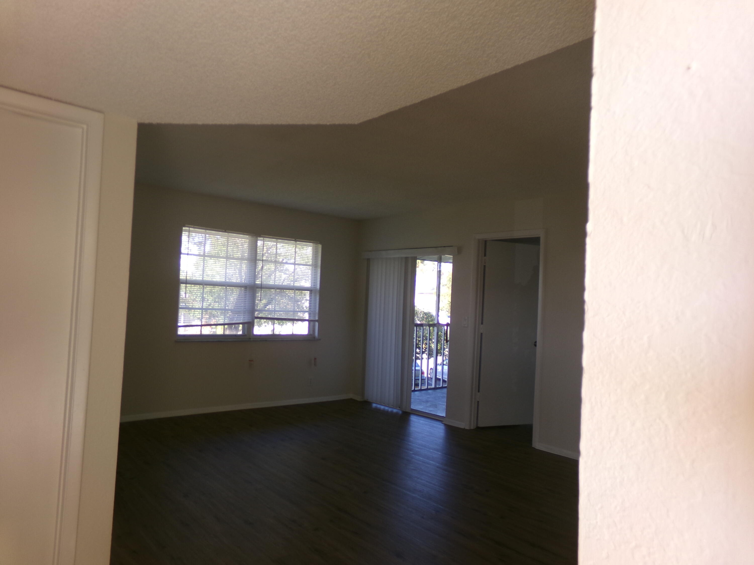 1514 Southeast Royal Green Circle, Unit I203 Port St. Lucie, FL 34952 - Photo 3 of 13 a view of an empty room with wooden floor and a window