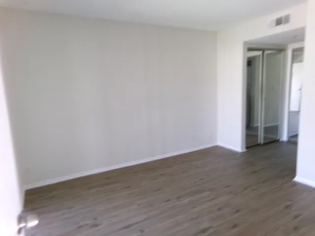 a view of an empty room with wooden floor and closet