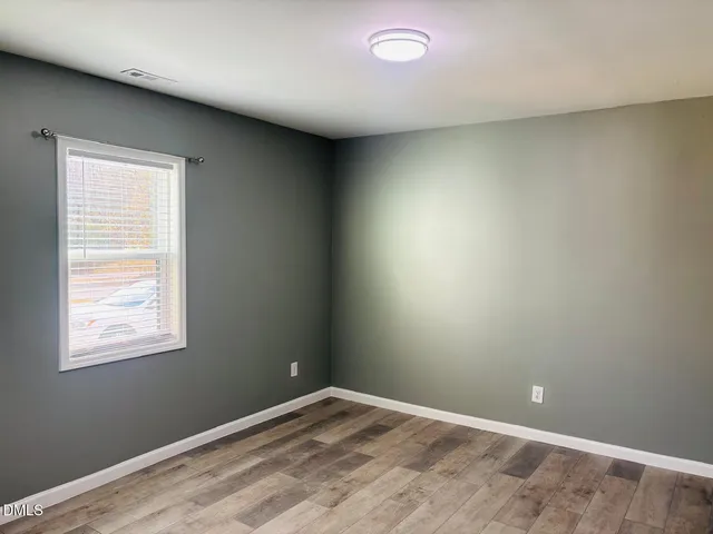 an empty room with wooden floor and entrance