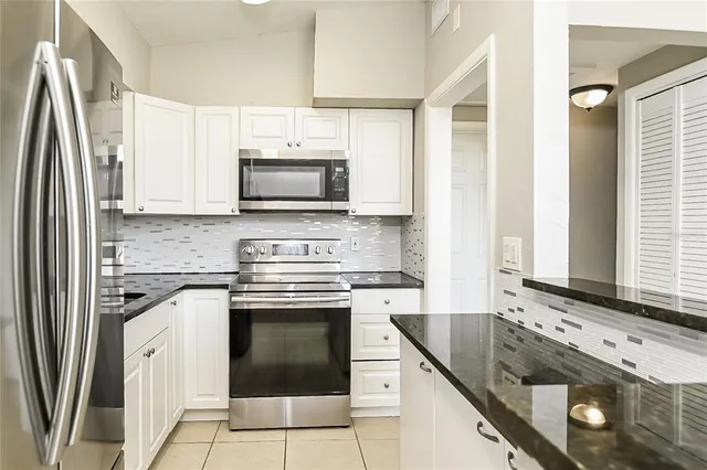 a kitchen with granite countertop a stove sink and refrigerator