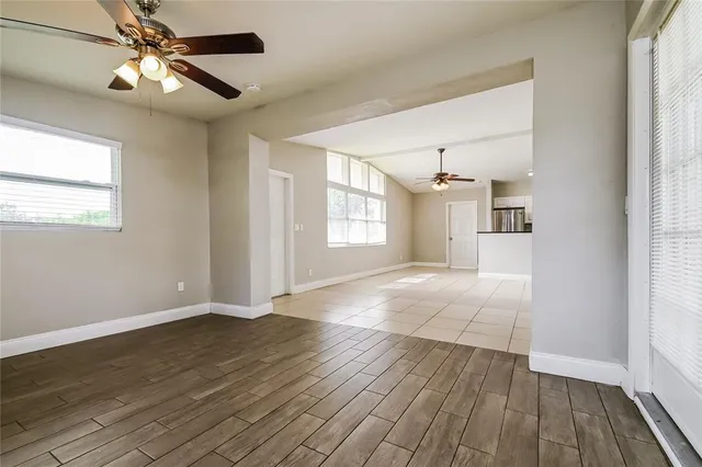 a view of an empty room with window and wooden floor