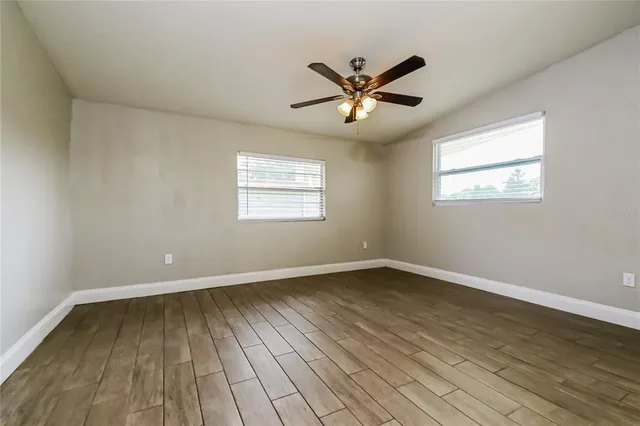 a view of empty room with wooden floor and fan