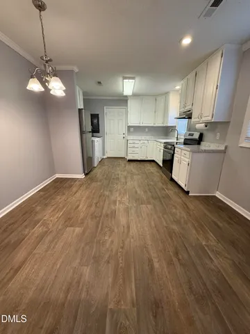 a large kitchen with kitchen island white cabinets and stainless steel appliances