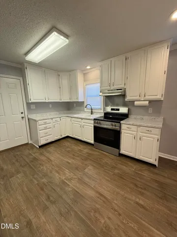 a kitchen with stainless steel appliances granite countertop a stove a sink and white cabinets