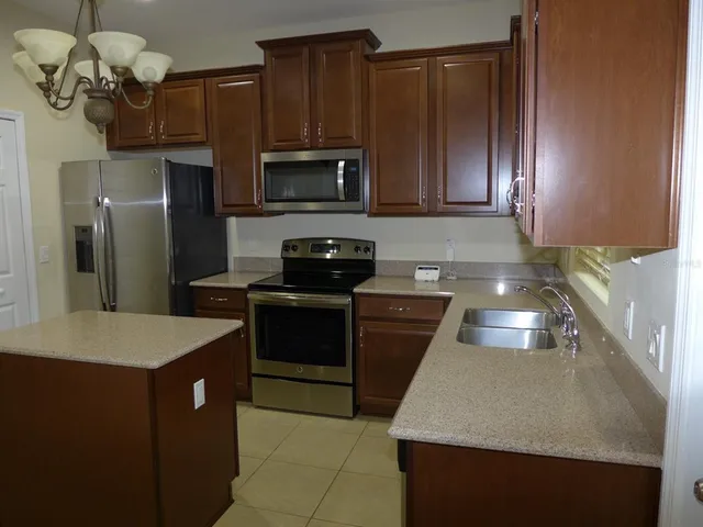 a kitchen with kitchen island granite countertop stainless steel appliances a stove microwave and refrigerator