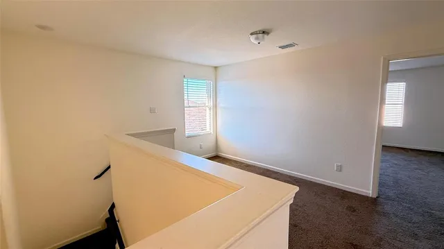 a view of an empty room with window and wooden floor