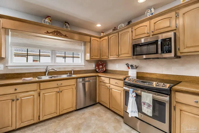 a kitchen with stainless steel appliances kitchen island granite countertop a table chairs sink and cabinets