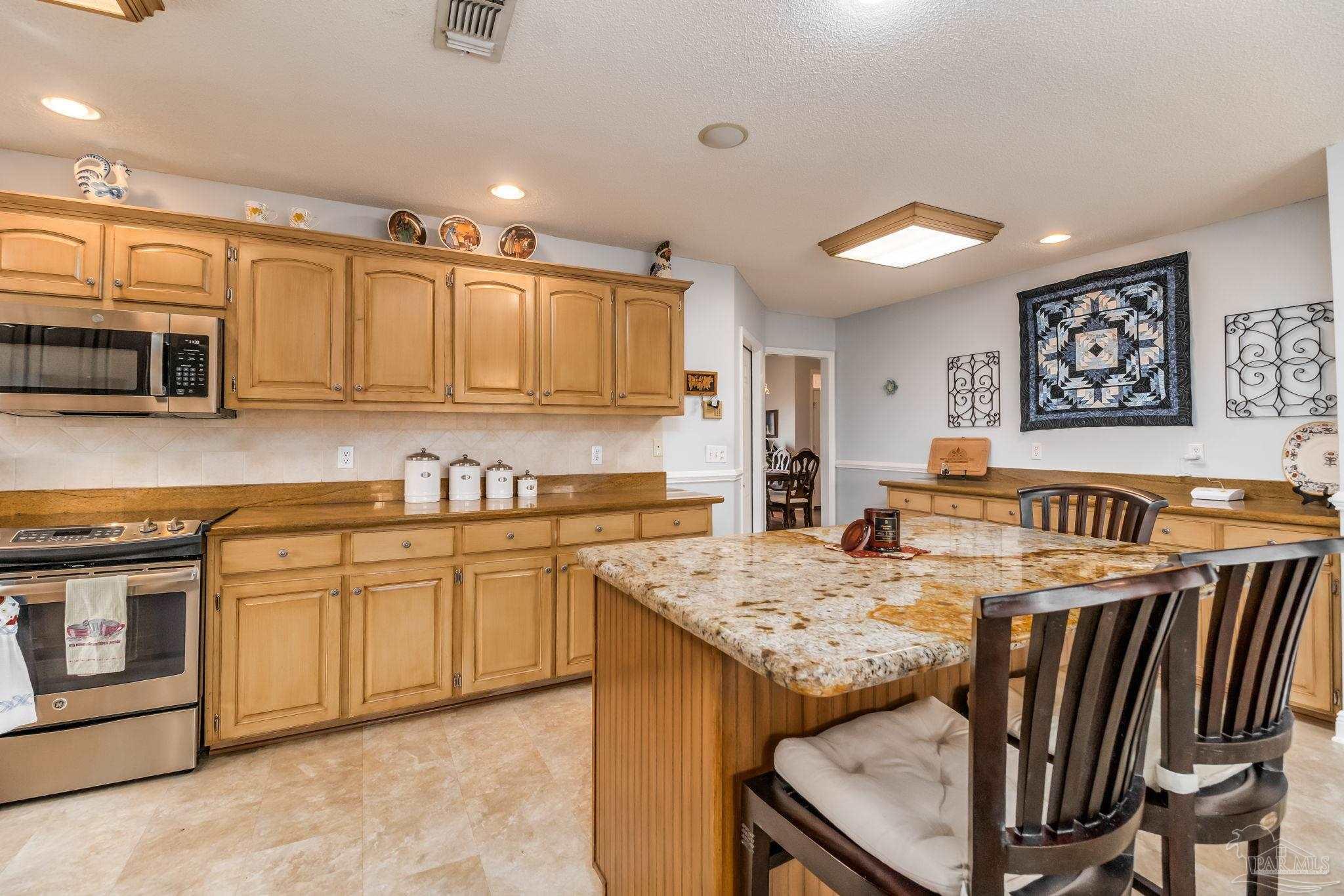 3106 Cobblestone Drive Pace, FL 32571 - Photo 16 of 61 a kitchen with stainless steel appliances granite countertop a stove top oven a sink a dining table and chairs