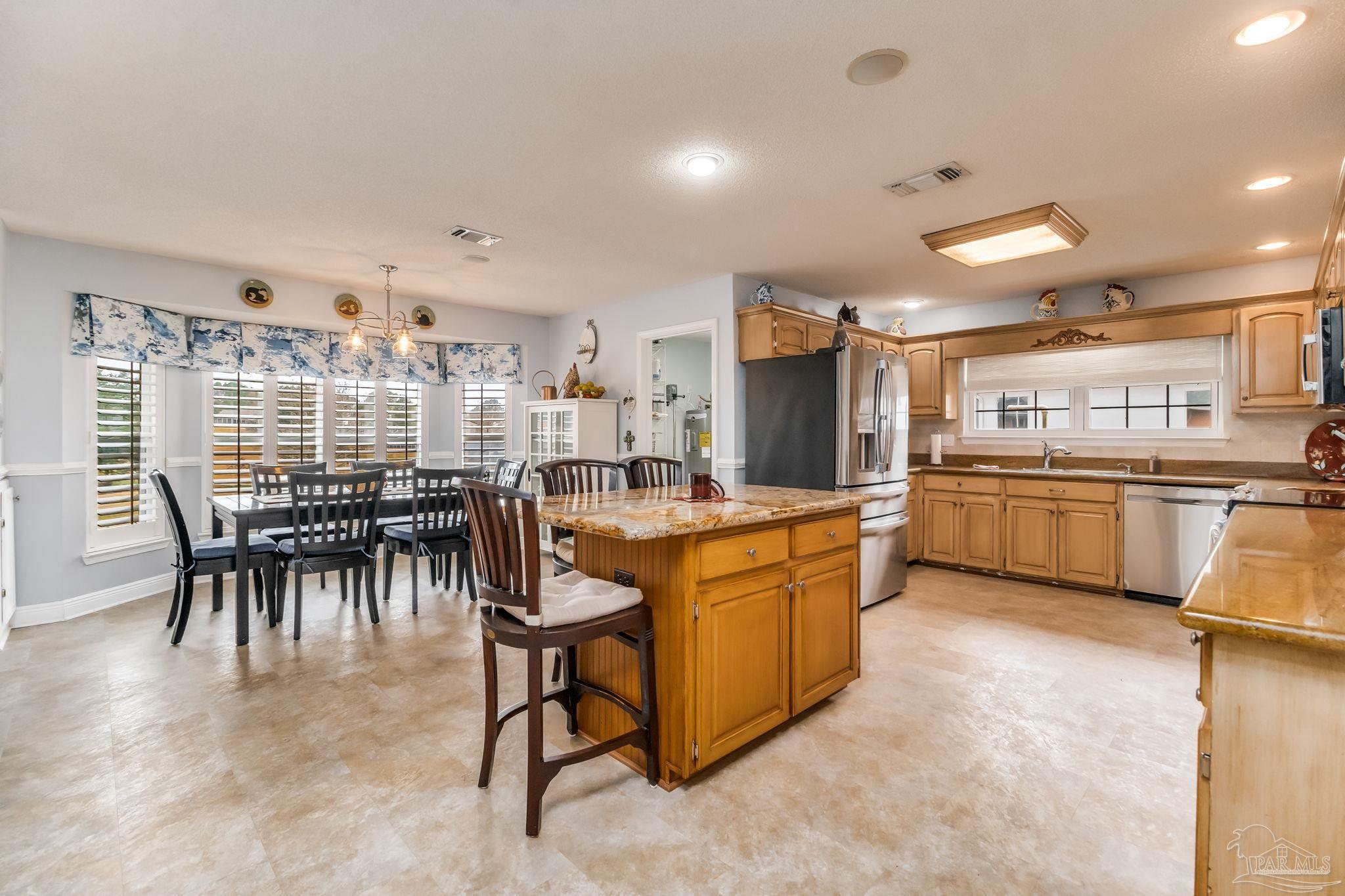 3106 Cobblestone Drive Pace, FL 32571 - Photo 17 of 61 a kitchen with stainless steel appliances kitchen island granite countertop a table chairs sink and cabinets