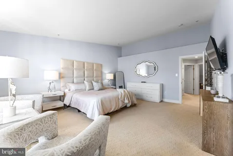 a spacious bedroom with a bed a mirror and lamp