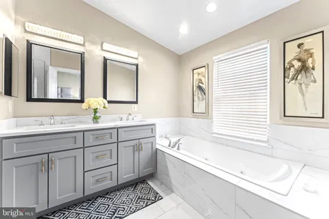 a bathroom with a tub a sink and a large mirror