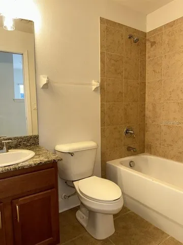 a bathroom with a granite countertop bathtub shower sink mirror vanity and toilet