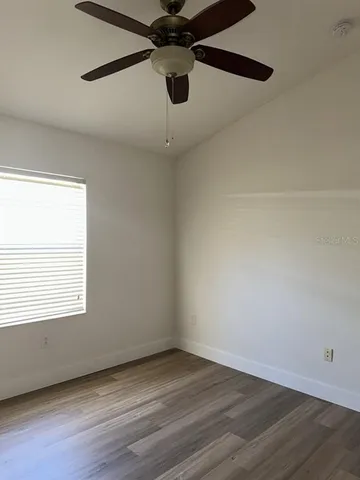 a view of an empty room with wooden floor and a window