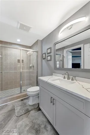 a bathroom with a granite countertop sink toilet a large mirror a shower and vanity