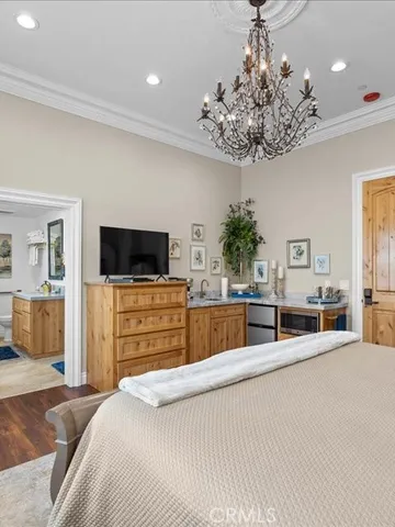 a view of an empty room with wooden floor and kitchen space