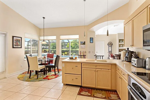 a view of a kitchen with kitchen island granite countertop a dining table chairs and a large window