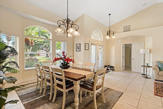 a view of a dining room with furniture a chandelier and large windows