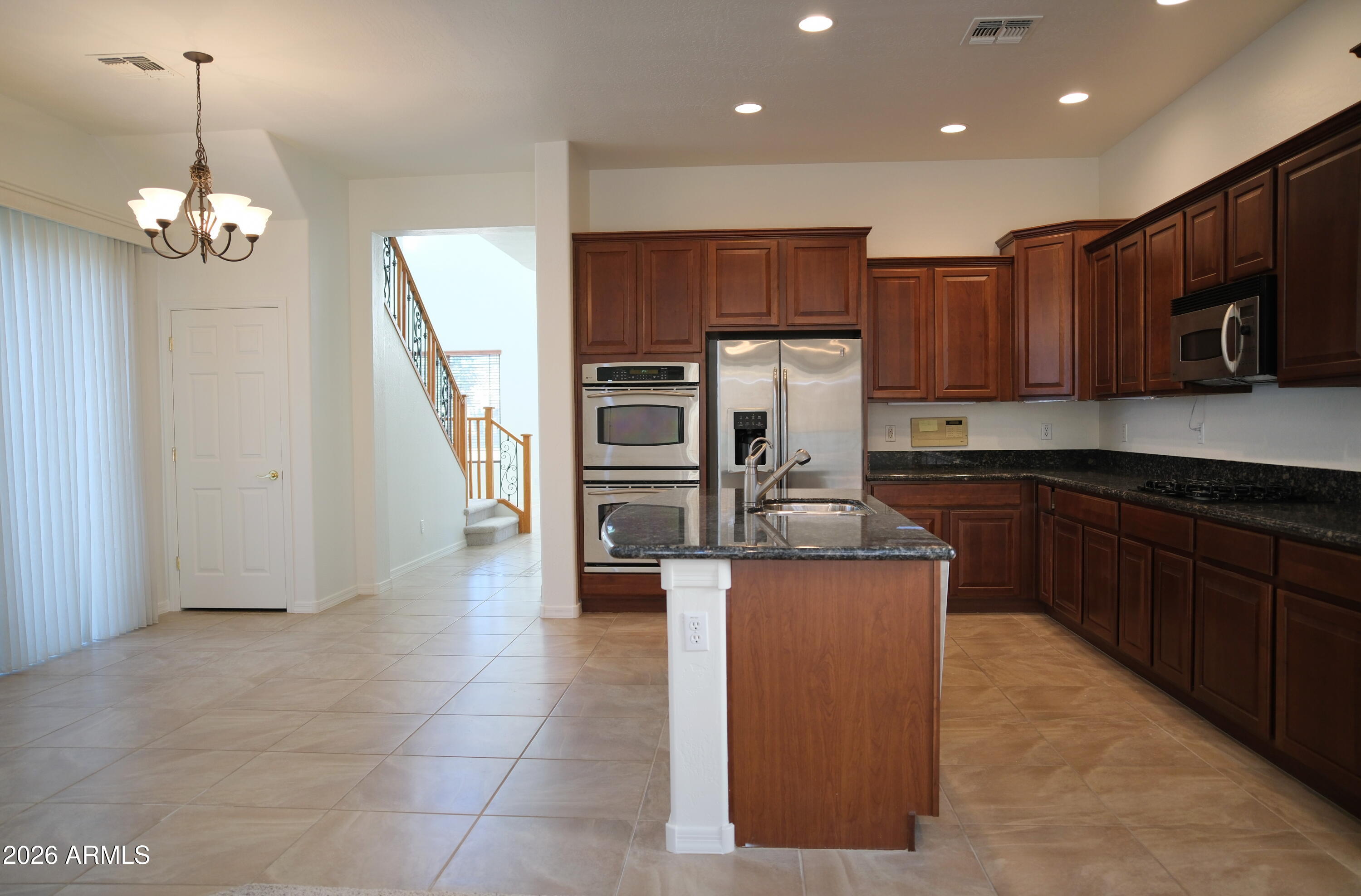 8367 West Briles Road Peoria, AZ 85383 - Photo 11 of 30 a kitchen with kitchen island granite countertop stainless steel appliances a sink a stove top oven a refrigerator and cabinets