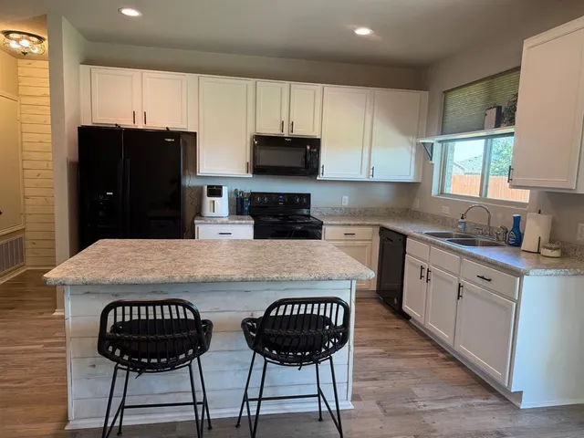 a kitchen with stainless steel appliances granite countertop a stove top oven a sink a refrigerator and a stove