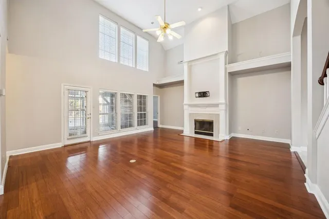 an empty room with wooden floor fireplace and windows