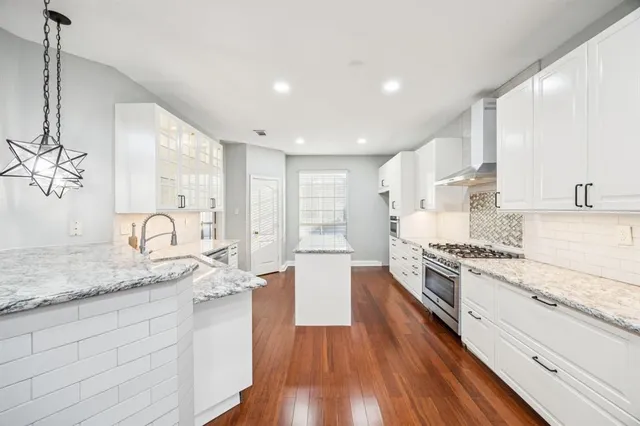 a large kitchen with granite countertop a stove top oven a sink a counter space and cabinets