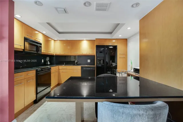 a kitchen with kitchen island granite countertop a sink a counter top space cabinets and stainless steel appliances