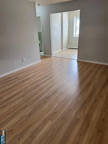a view of an empty room with wooden floor and windows