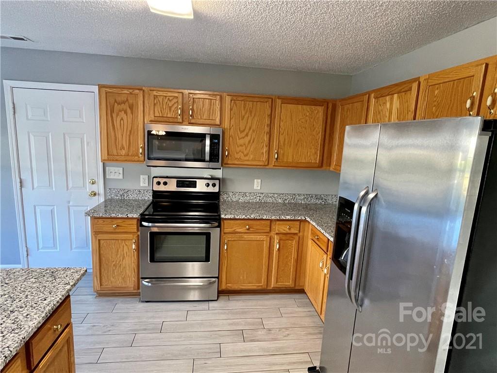 5514 Rogers Road Indian Trail, NC 28079 - Photo 13 of 34 a kitchen with granite countertop a refrigerator and a stove top oven