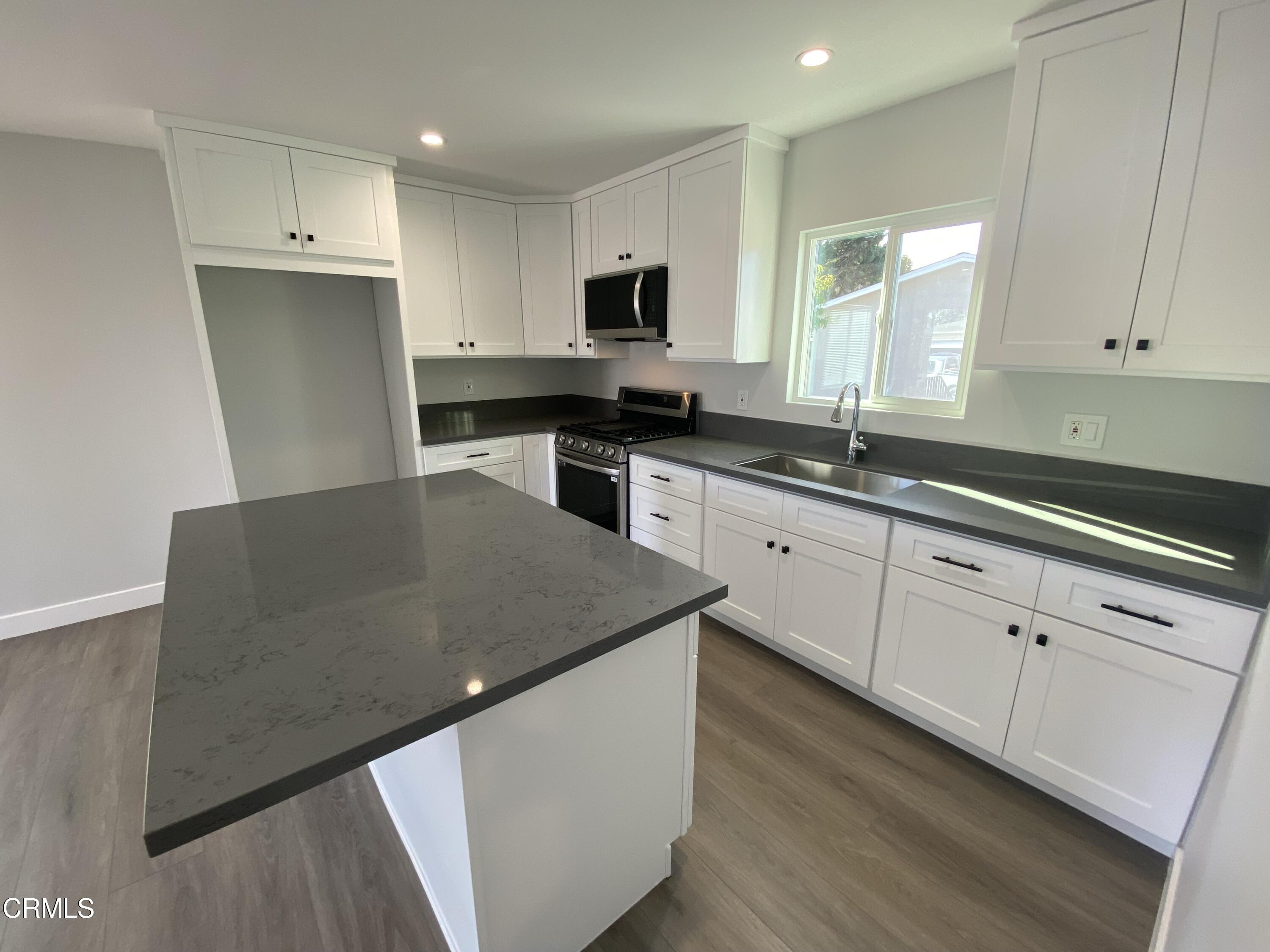 4931 Refsing Place Oxnard, CA 93033 - Photo 2 of 16 a kitchen with granite countertop a sink a stove top oven and cabinetry