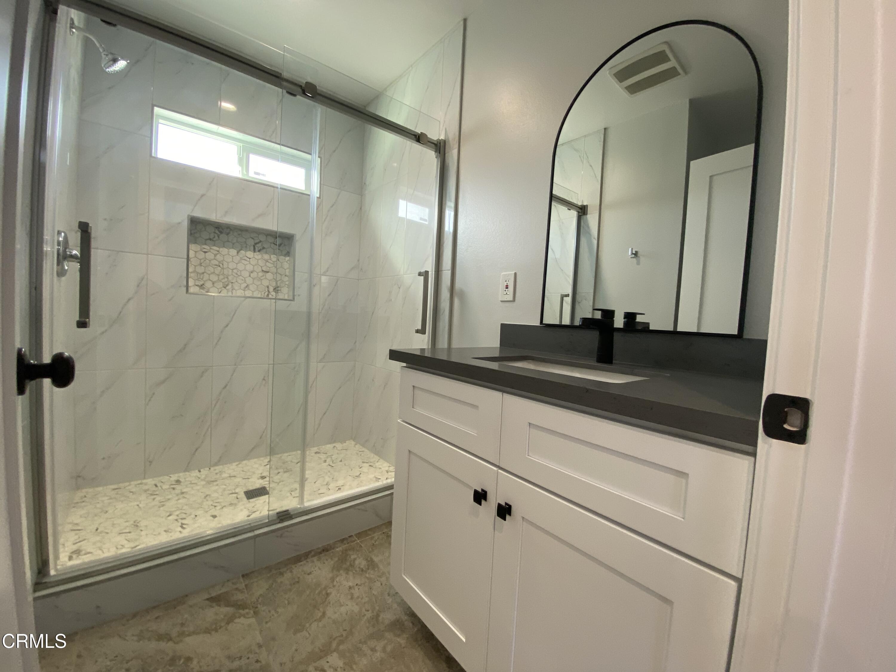 4931 Refsing Place Oxnard, CA 93033 - Photo 4 of 16 a bathroom with a granite countertop sink a mirror and a glass door shower
