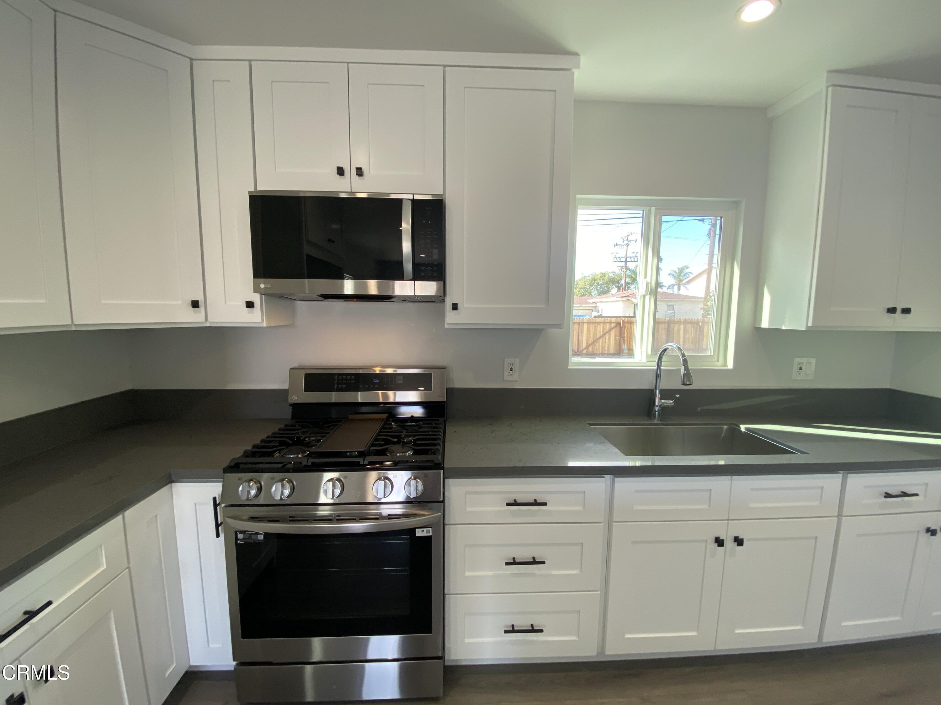 4931 Refsing Place Oxnard, CA 93033 - Photo 5 of 16 a kitchen with granite countertop white cabinets and a stove a sink