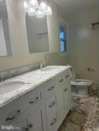 a bathroom with a granite countertop toilet sink and mirror