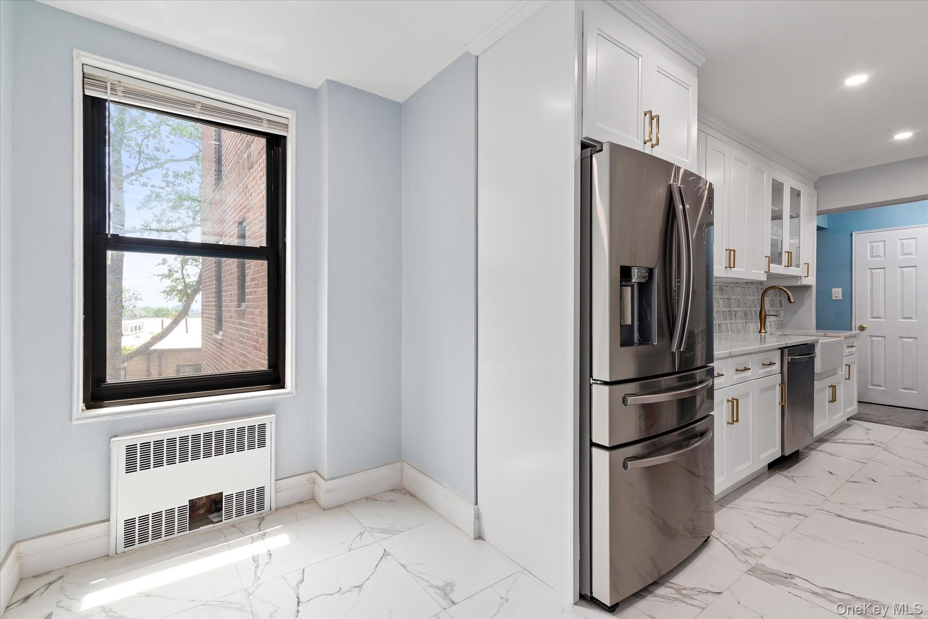 83-30 98th Street, Unit 5A Queens, NY 11421 - Photo 8 of 15 Kitchen with appliances with stainless steel finishes, radiator heating unit, light marble finish flooring, baseboards, and recessed lighting