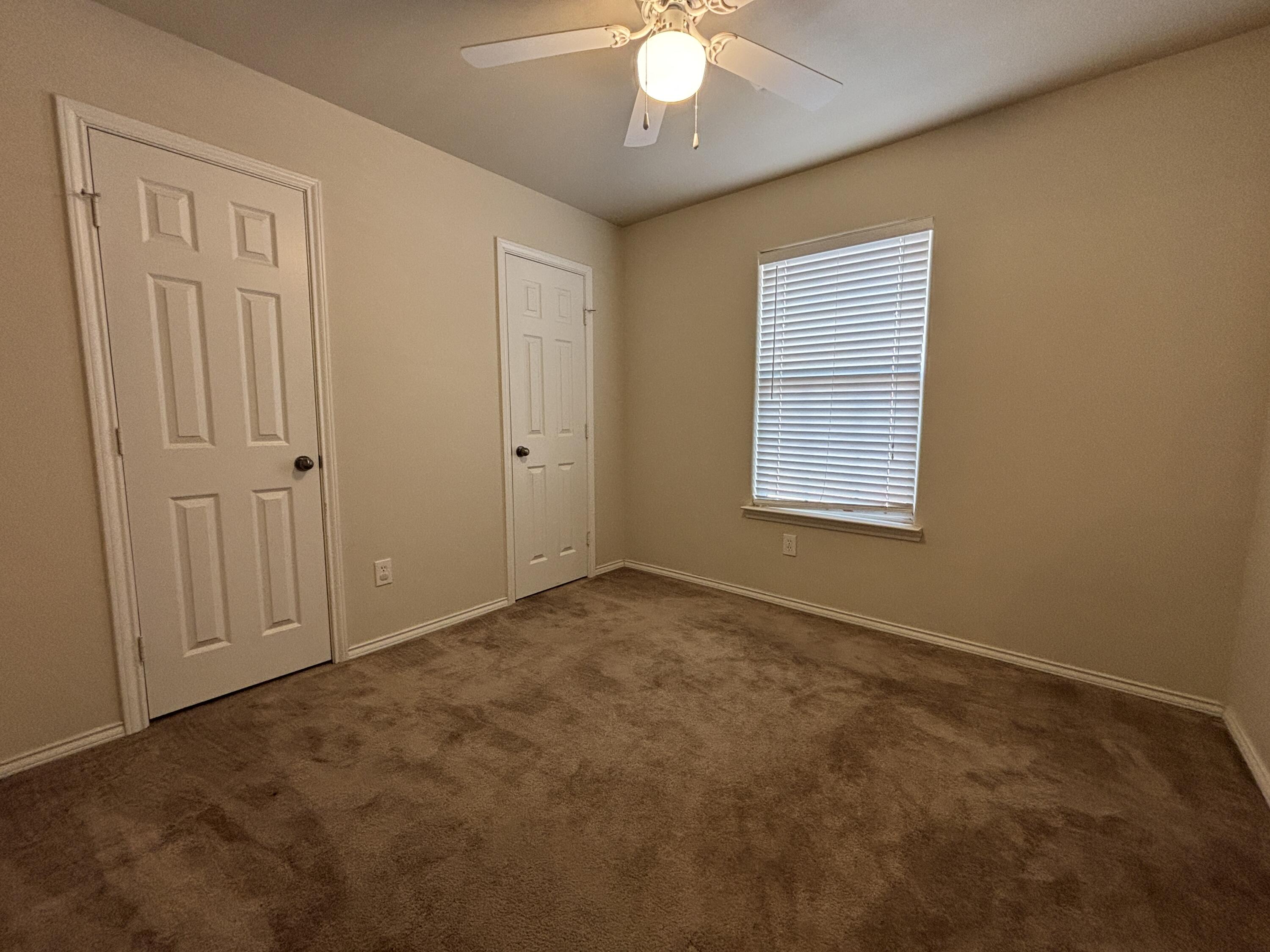 6515 92nd Street Lubbock, TX 79424 - Photo 7 of 9 an empty room with a chandelier fan and windows