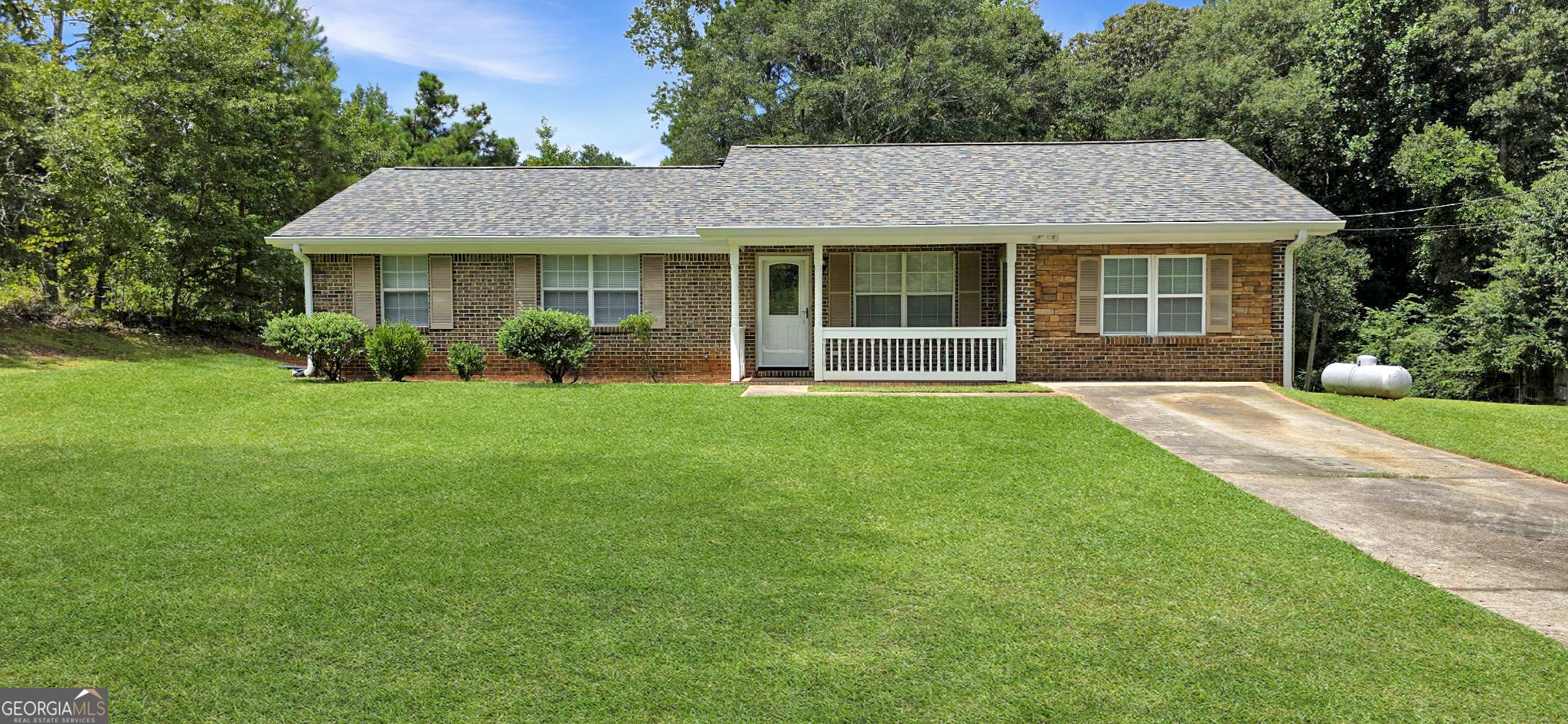 a front view of a house with a yard and green space
