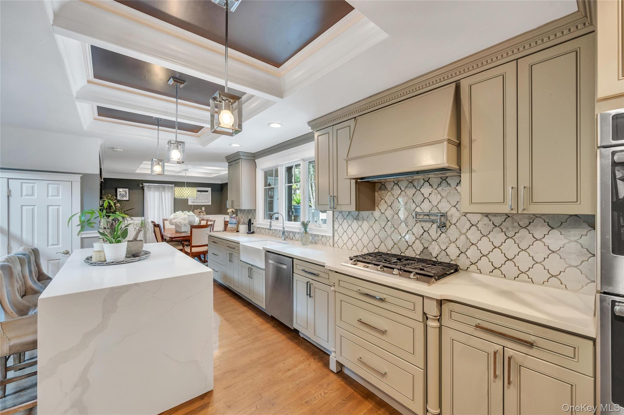 19 Joan Road Bay Shore, NY 11706 - Photo 13 of 50 Kitchen featuring a waterfall island with a light-toned countertop, pendant lighting, recessed lighting, wood-finish flooring, and light-toned cabinetry with a decorative backsplash