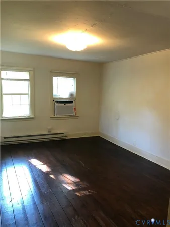 en empty room with wooden floor and windows