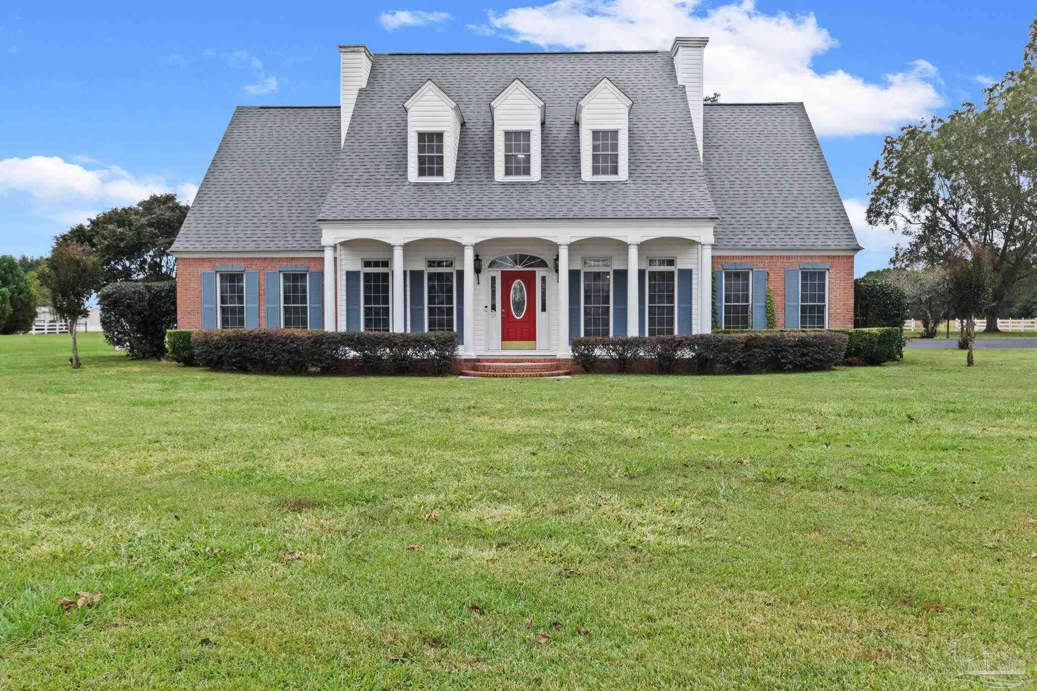 a front view of a house with garden and trees