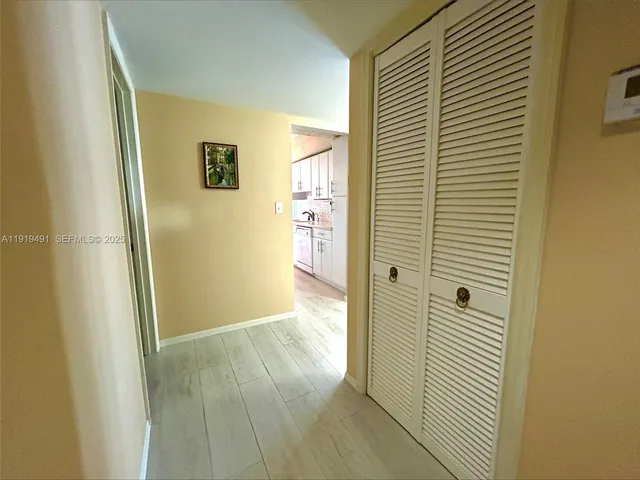 a view of a hallway with wooden floor and a bathroom