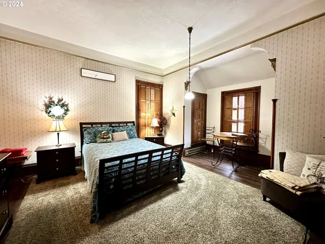 a bedroom with a bed dresser and wooden floor