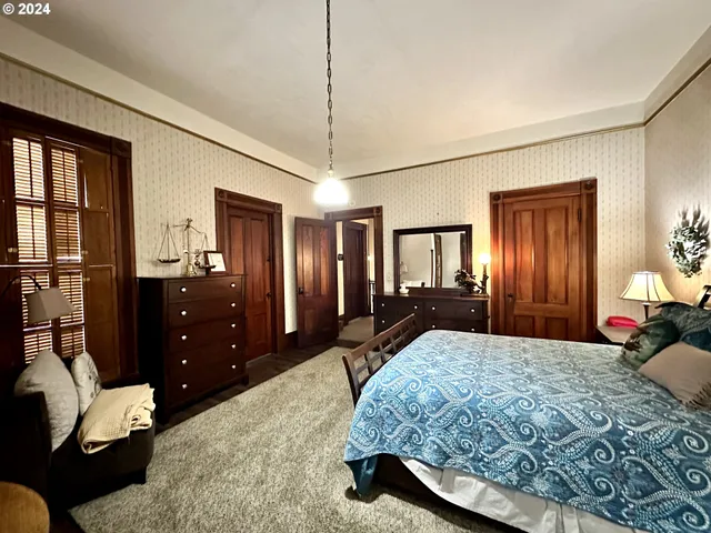 a bedroom with a bed dresser and windows