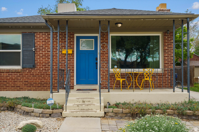 961 33rd Street Ogden, UT 84403 - Photo 5 of 39 Brick exterior featuring a covered porch with decorative metal supports, an accent blue entry door, and a large front picture window