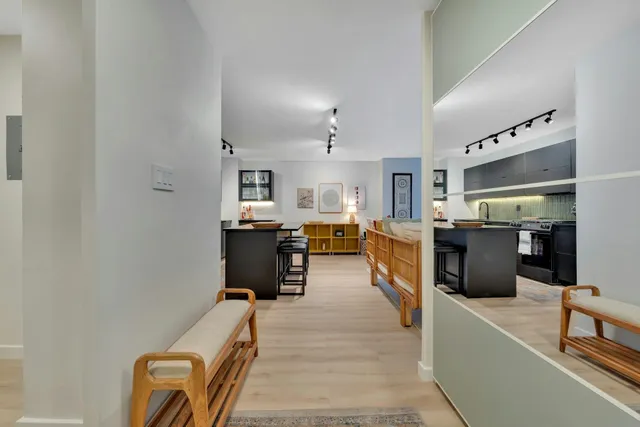 a view of a hallway with wooden floor and a bathroom