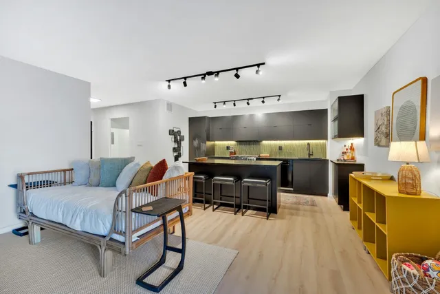 a spacious bedroom with a bed and a flat tv screen on dresser