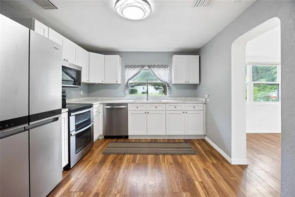 a kitchen with a white cabinets and wooden floor