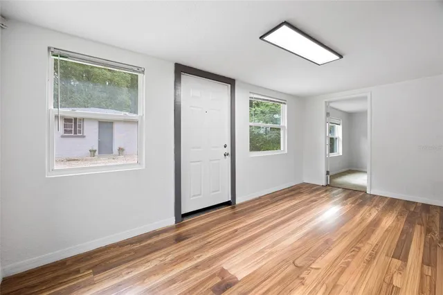 a view of an empty room with wooden floor and a window