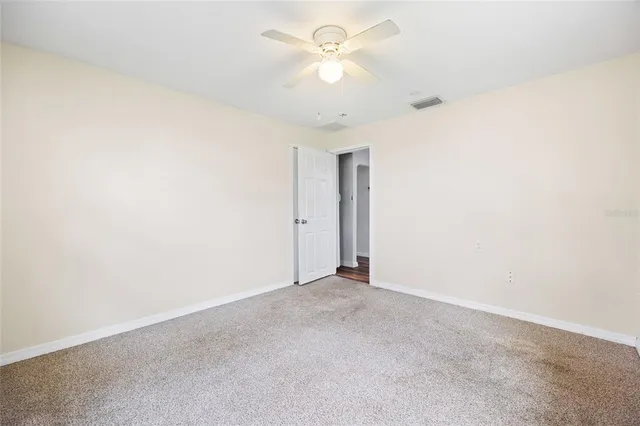 an empty room with a chandelier fan and closet